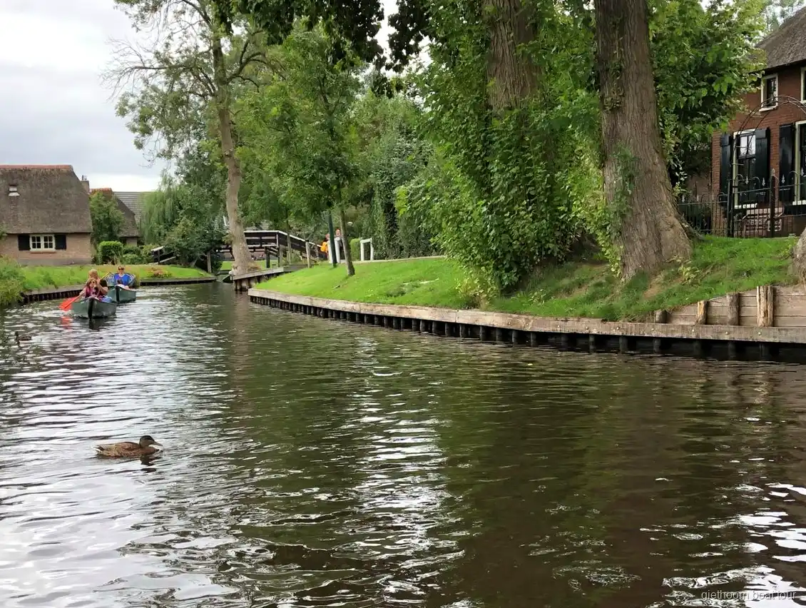 Zelfvaar boot vaart onder een houten boogbrug in Giethoorn