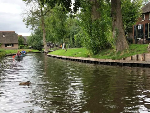 Bateau sans permis passant sous un pont en bois en arc à Giethoorn