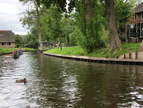 Selbstfahrer-Boot passiert eine hölzerne Bogenbrücke in Giethoorn