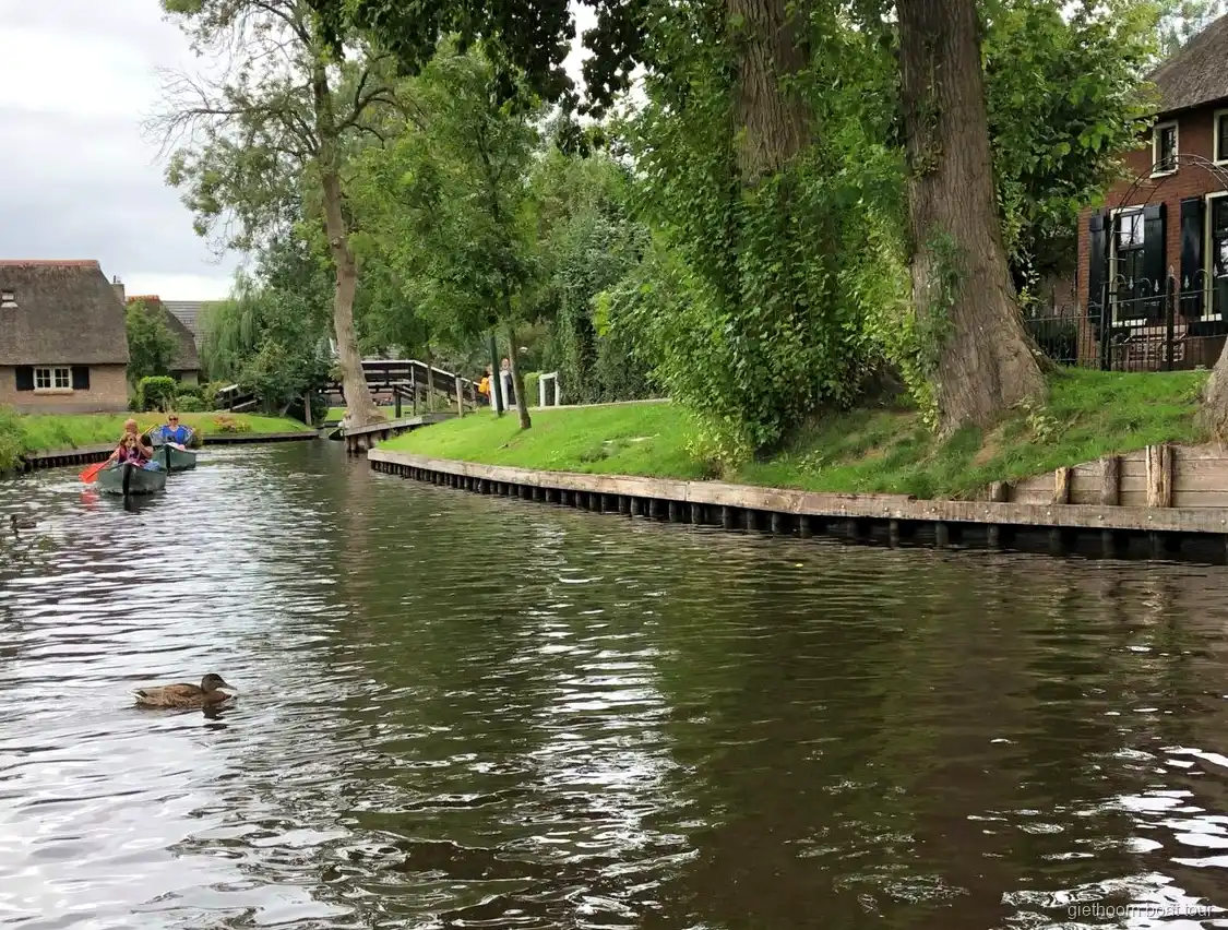 Selbstfahrer-Boot passiert eine hölzerne Bogenbrücke in Giethoorn