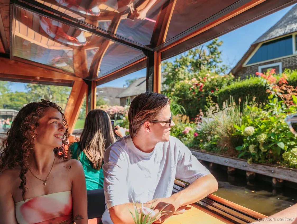 Bateau de croisière passant devant des fermes aux toits de chaume à Giethoorn