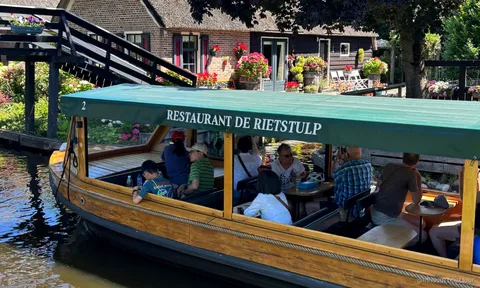 Giethoorn canal cruise passing thatched-roof farmhouses near the village center