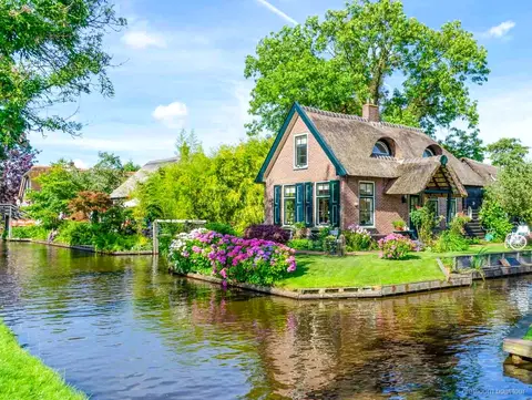 Coppia che guida la propria barca a noleggio attraverso un canale di Giethoorn